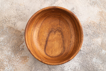 Empty brown wooden bowl on brown concrete. Top view, copy space