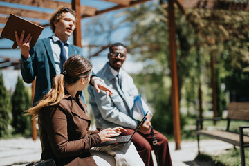 A multiracial group of businesspeople engaged in an outdoor meeting in a sunlit city park. Executives discussing and sharing ideas passionately, demonstrating teamwork and cooperation.