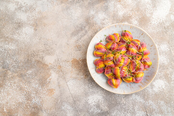 Rainbow colored dumplings with microgreen on brown concrete. Top view, flat lay, copy space.