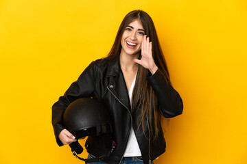Young caucasian woman holding a motorcycle helmet isolated on yellow background shouting with mouth...