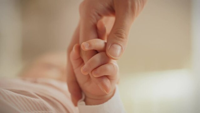 Mom gently holds her baby's hand, touching it with love and trepidation. This vivid image captures the deep connection and tenderness that fills every moment of motherhood