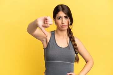 Sport caucasian woman isolated on yellow background showing thumb down with negative expression
