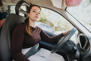 Young adult female in casual wear, driving her vehicle with concentration and safety on a busy...