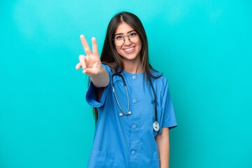 Young nurse caucasian woman isolated on blue background smiling and showing victory sign