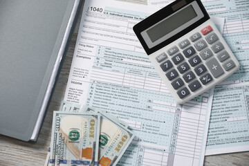 Payroll. Tax return forms, calculator and dollar banknotes on wooden table, flat lay
