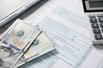 Obraz premium Payroll. Tax return form, calculator and dollar banknotes on table, selective focus