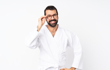 Young man doing karate over isolated white background with glasses and happy