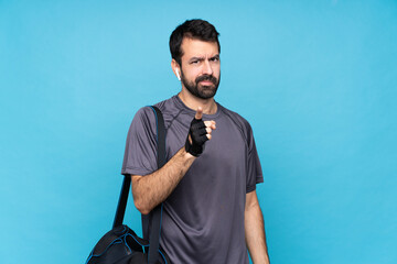 Young sport man with beard over isolated blue background frustrated and pointing to the front