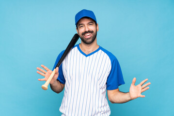 Young man playing baseball over isolated blue background smiling