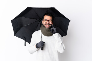 Caucasian handsome man with beard holding an umbrella over isolated white wall smiling with a happy and pleasant expression