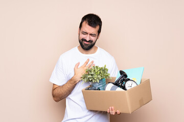 Man holding a box and moving in new home over isolated background having a pain in the heart