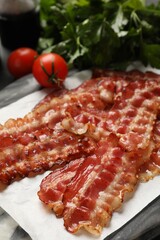 Obraz premium Fried bacon slices and tomatoes on marble board, closeup