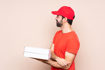 Young man holding a pizza over isolated background in lateral position