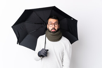 Caucasian handsome man with beard holding an umbrella over isolated white wall with sad and depressed expression