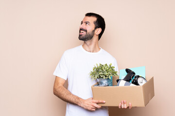 Man holding a box and moving in new home over isolated background happy and smiling