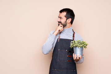 Man holding a plant over isolated background looking to the side