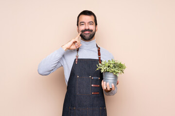 Man holding a plant over isolated background smiling with a happy and pleasant expression