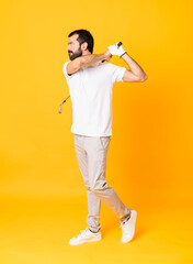 Full-length shot of man over isolated yellow background playing golf