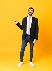 Full-length shot of business man over isolated yellow background pointing finger to the side