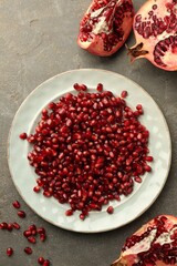 Tasty ripe pomegranate and grains on grey table, flat lay