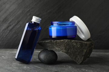 Cosmetic products and stones on grey background