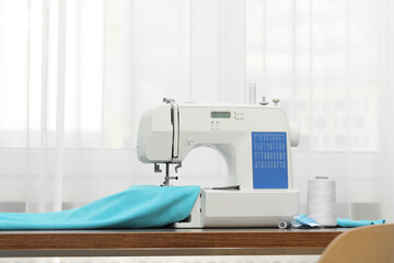 Sewing machine with fabric and craft accessories on wooden table indoors