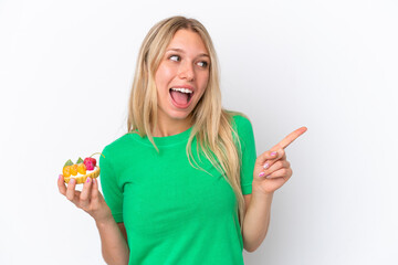 Young caucasian woman holding a tartlet isolated on white background intending to realizes the solution while lifting a finger up - obrazy, fototapety, plakaty