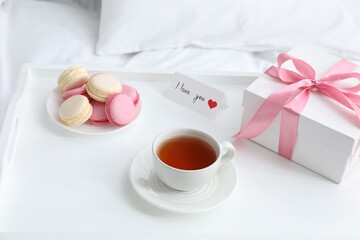 Tasty breakfast served in bed. Delicious eclairs, tea, gift box and I Love You card on tray