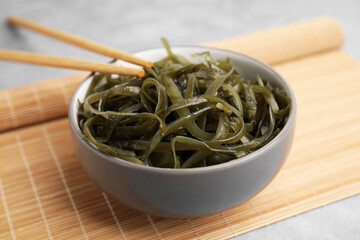 Tasty seaweed salad in bowl served on gray table, closeup