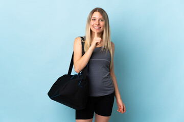 Young sport woman with sport bag isolated on blue background showing a sign of silence gesture...