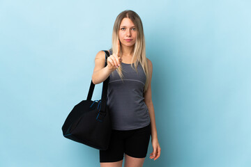 Young sport woman with sport bag isolated on blue background counting one with serious expression