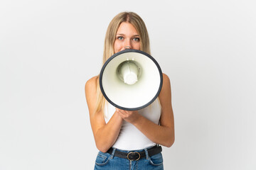 Young blonde woman isolated on white background shouting through a megaphone to announce something