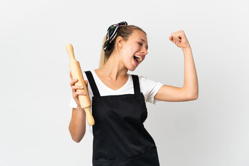 Young woman holding a rolling pin isolated on white background celebrating a victory