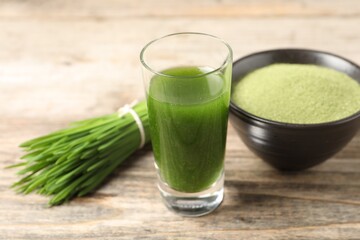 Wheat grass drink in shot glass on wooden table, closeup