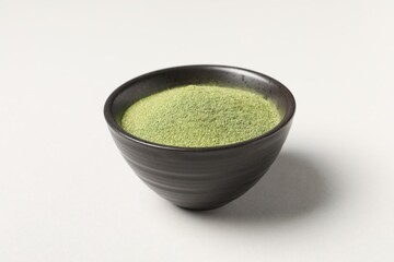 Wheat grass powder in bowl on light table, closeup