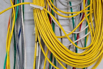 Colorful CAT5 Twisted pair cables electrical cords hanging on wall computer networks equipment.	
