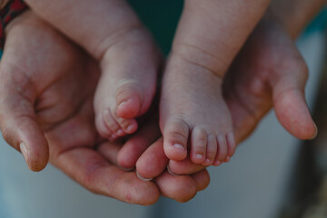 Father and son showing hands and feet of a new born