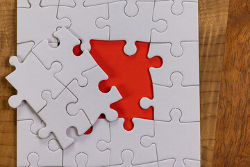 Blank puzzle with one missing piece next to the whole with a red placer where the last piece belongs. Concept for problem solving.