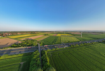 Highway cutting through lush green fields in a natural landscape under blue sky panorama drone view Hanover Wunstorf Kolenfeld Germany 