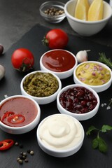 Different tasty sauces in bowls and ingredients on table