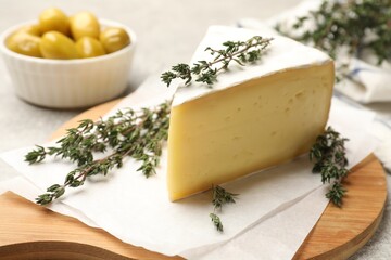Piece of tasty camembert cheese and thyme on table, closeup