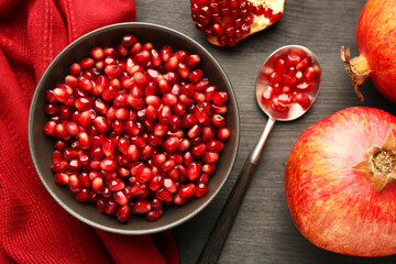 Tasty ripe pomegranates and grains on dark wooden table, flat lay