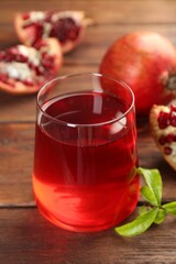 Tasty pomegranate juice in glass and fresh fruits on wooden table, closeup