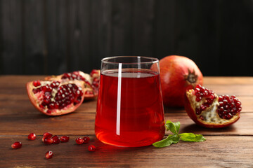 Tasty pomegranate juice in glass and fresh fruits on wooden table