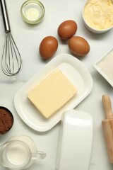 Flat lay composition with fresh butter among other products on white table