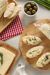 Tasty butter, olives, green onion and bread on wooden table, flat lay