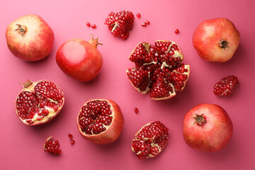 Whole and cut fresh pomegranates on pink background, flat lay