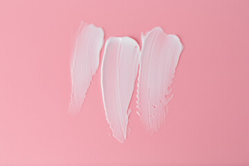 Sample of body care cream on pink background, top view
