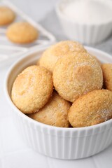 Tasty sugar cookies in bowl on white tiled table, closeup