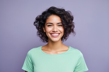 A woman with curly hair is smiling and wearing a green shirt